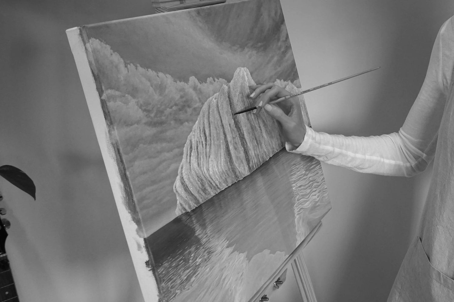 Australian artist, Hayley Byron, painting an iceberg in oil on linen. This image features the artist painting on the canvas with a paintbrush.