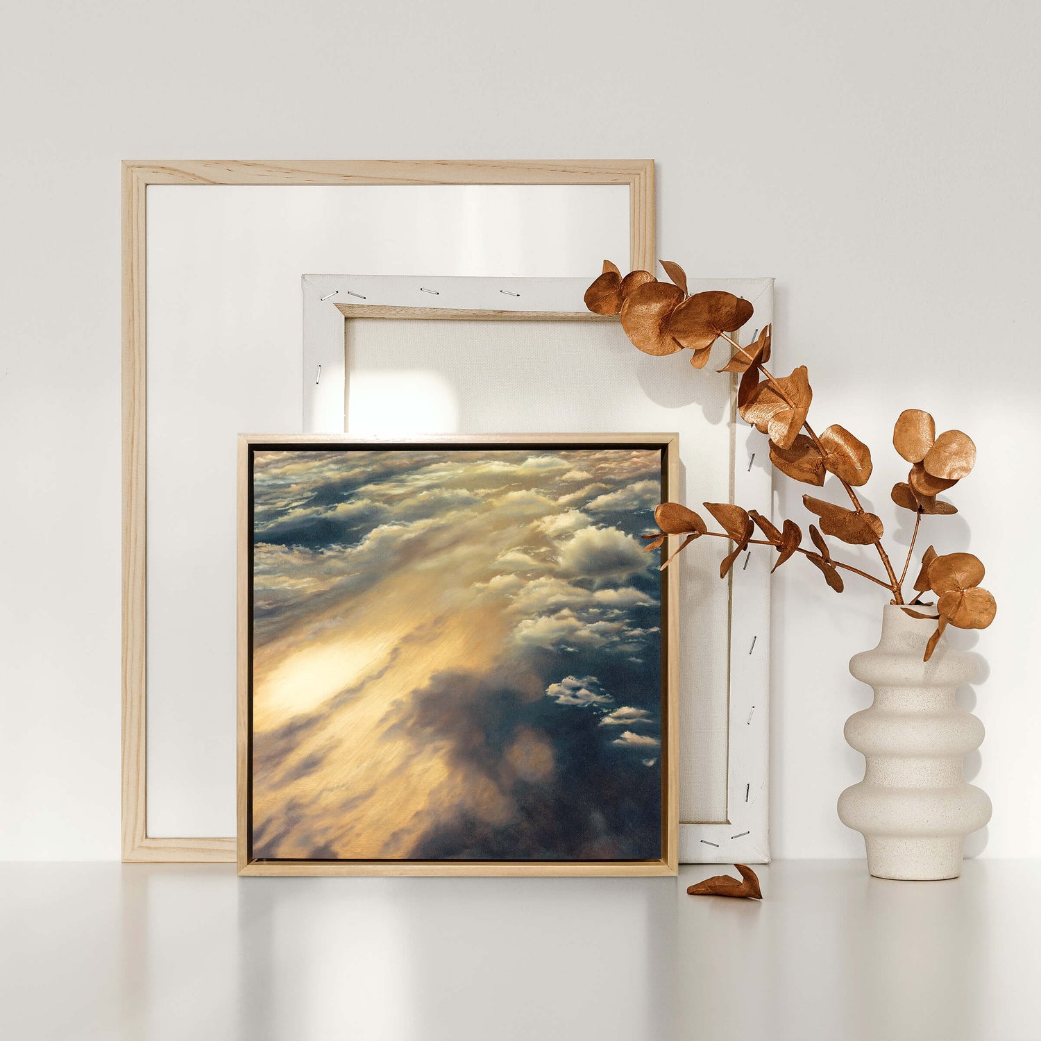 Original art, titled Cloudland, painted in oil on canvas, by Australian artist, Hayley Byron. The painting is a depiction of a cloudscape, from an aerial viewpoint. This image features the artwork in-situ, with stacked art canvasses, and a ceramic vase.