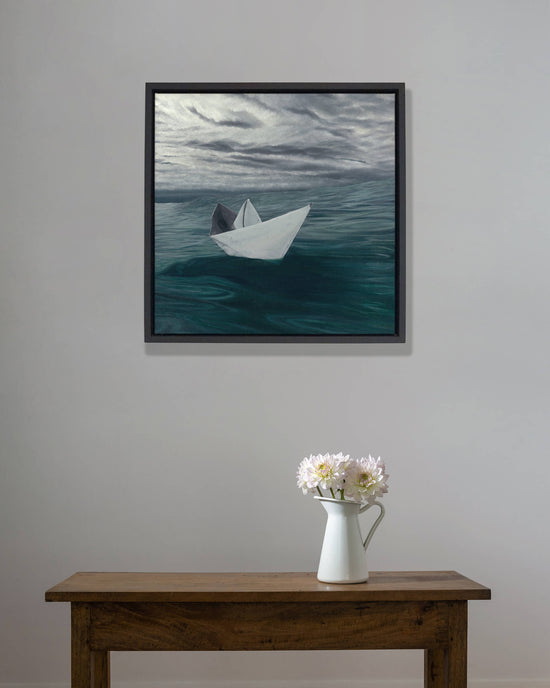 Original art, titled Hope, painted in water mixable oil on canvas, by Australian artist, Hayley Byron. The painting is a depiction of a paper boat in the ocean, with clouds in the background. This image features the artwork in-situ, in an interior room. 