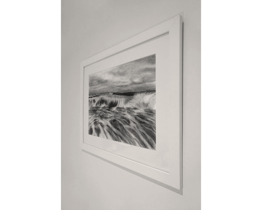 Original art, titled La Mar, hand-drawn in graphite and willow charcoal on fine art paper, by Australian artist, Hayley Byron. The drawing is a depiction of a wave in the ocean. This image features the artwork on a wall in a frame.