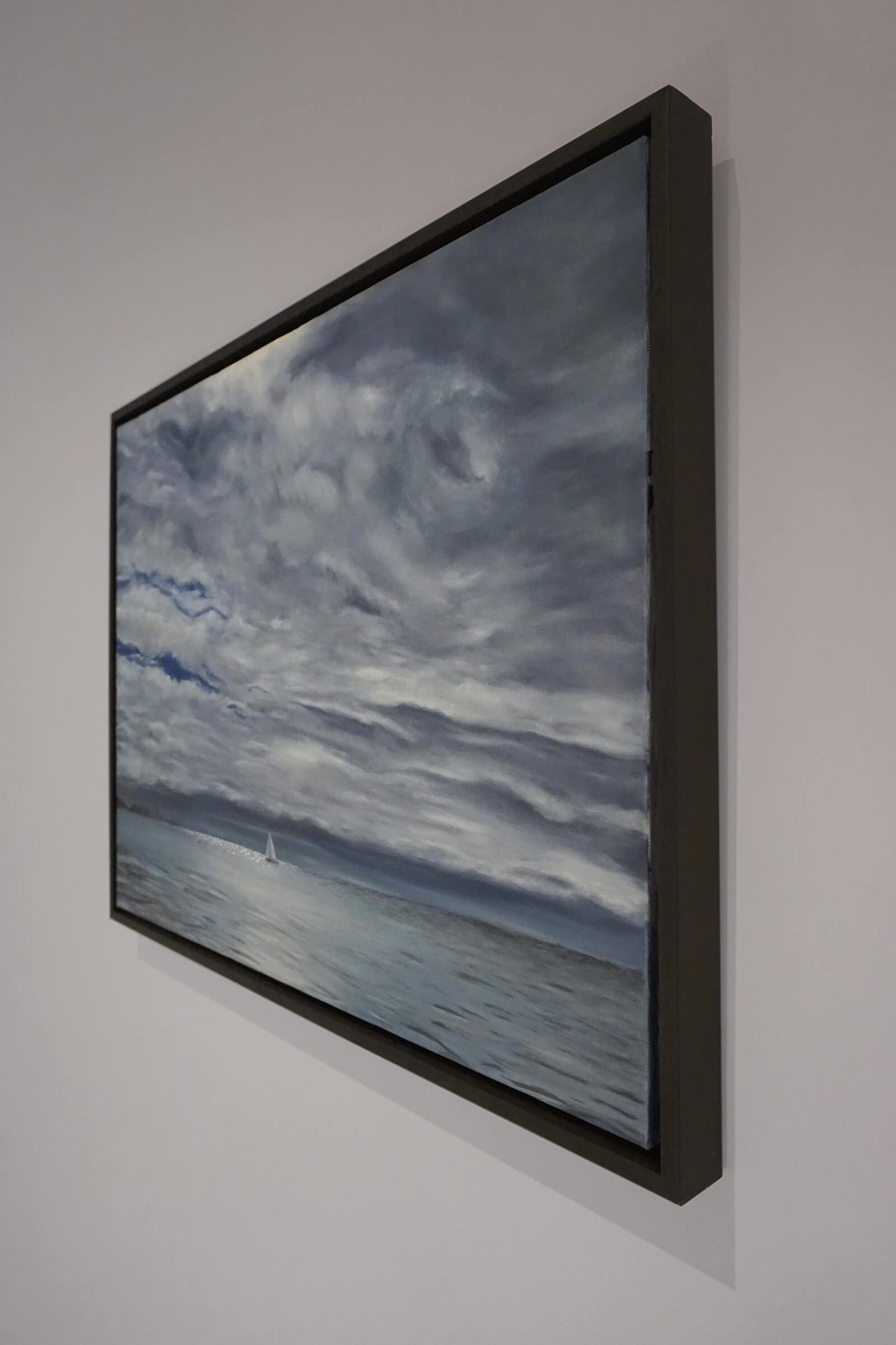 Original art, titled Yesterday, painted in oil on canvas, by Australian artist, Hayley Byron. The painting is a depiction of a ship sailing on the ocean at Burleigh Heads, in a rain storm, with high-rise buildings in the distance. This image features the artwork in-situ, on a wall in a custom-made frame.