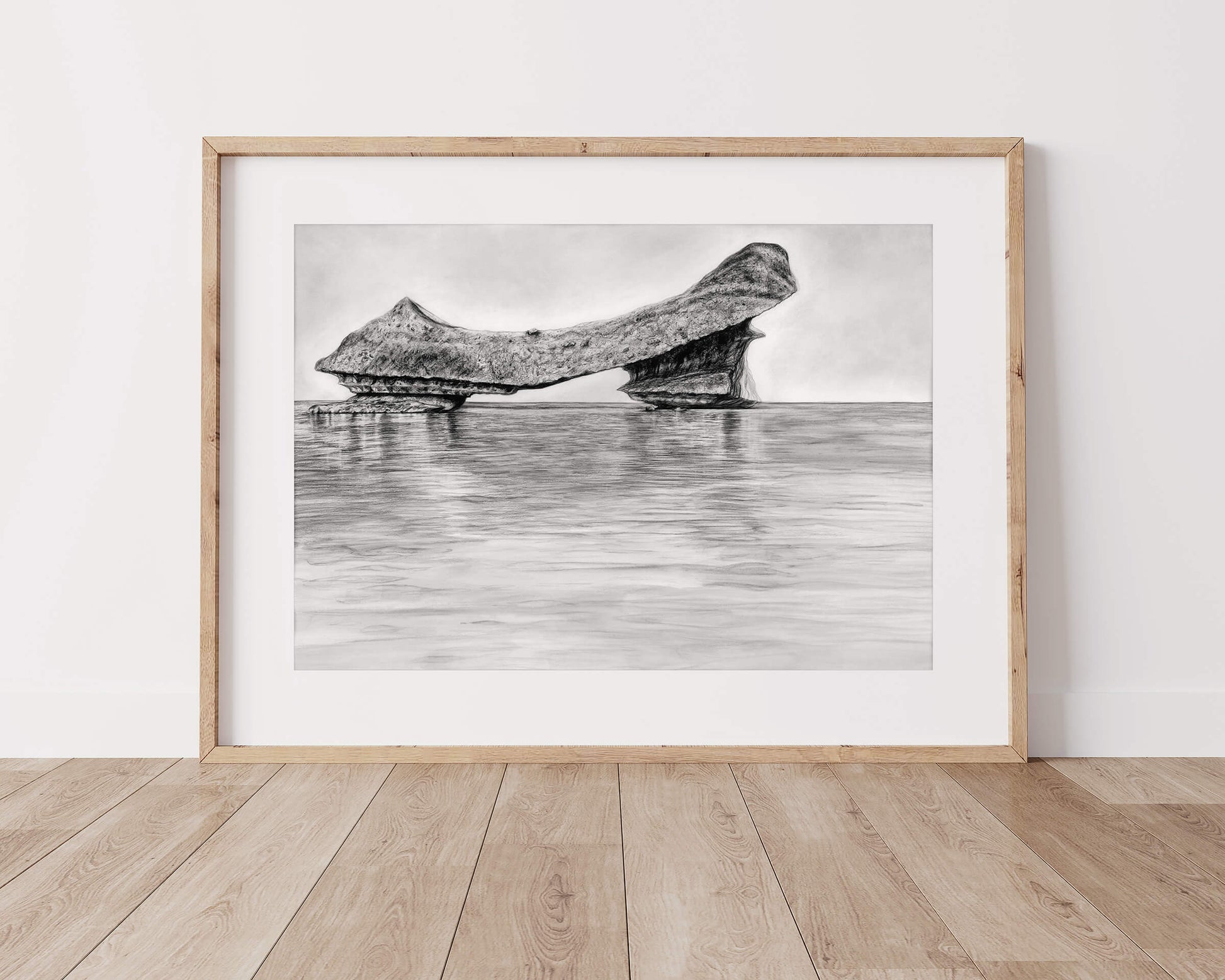 Original art, titled Grit, hand-drawn with graphite on fine art paper, by Australian artist, Hayley Byron. The drawing is a depiction of an iceberg, with water in the foreground. This image features the artwork in-situ, positioned on a timber floor, in a custom-made frame.