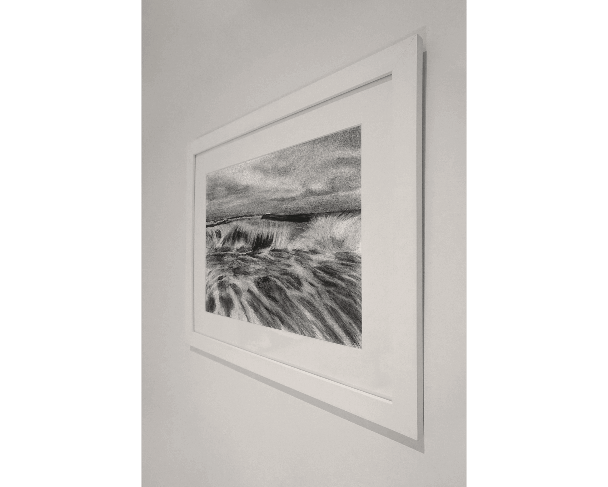 Original art, titled La Mar, hand-drawn in graphite and willow charcoal on fine art paper, by Australian artist, Hayley Byron. The drawing is a depiction of a wave in the ocean. This image features the artwork on a wall in a frame.