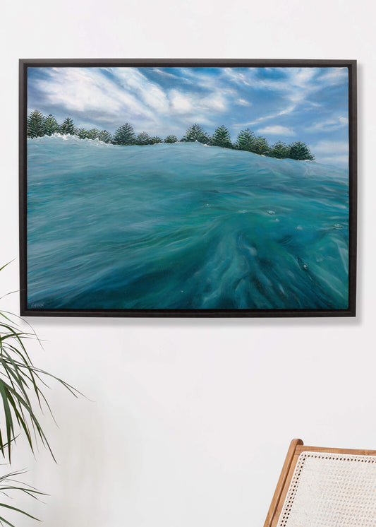 Original art, titled Playground, painted in oil on canvas, by Australian artist, Hayley Byron. The painting is a depiction of being in the ocean at Burleigh Heads, from the viewpoint of sitting out the back, with Norfolk Pine trees in the distance. This image features the artwork in-situ, on a wall in a custom-made frame.