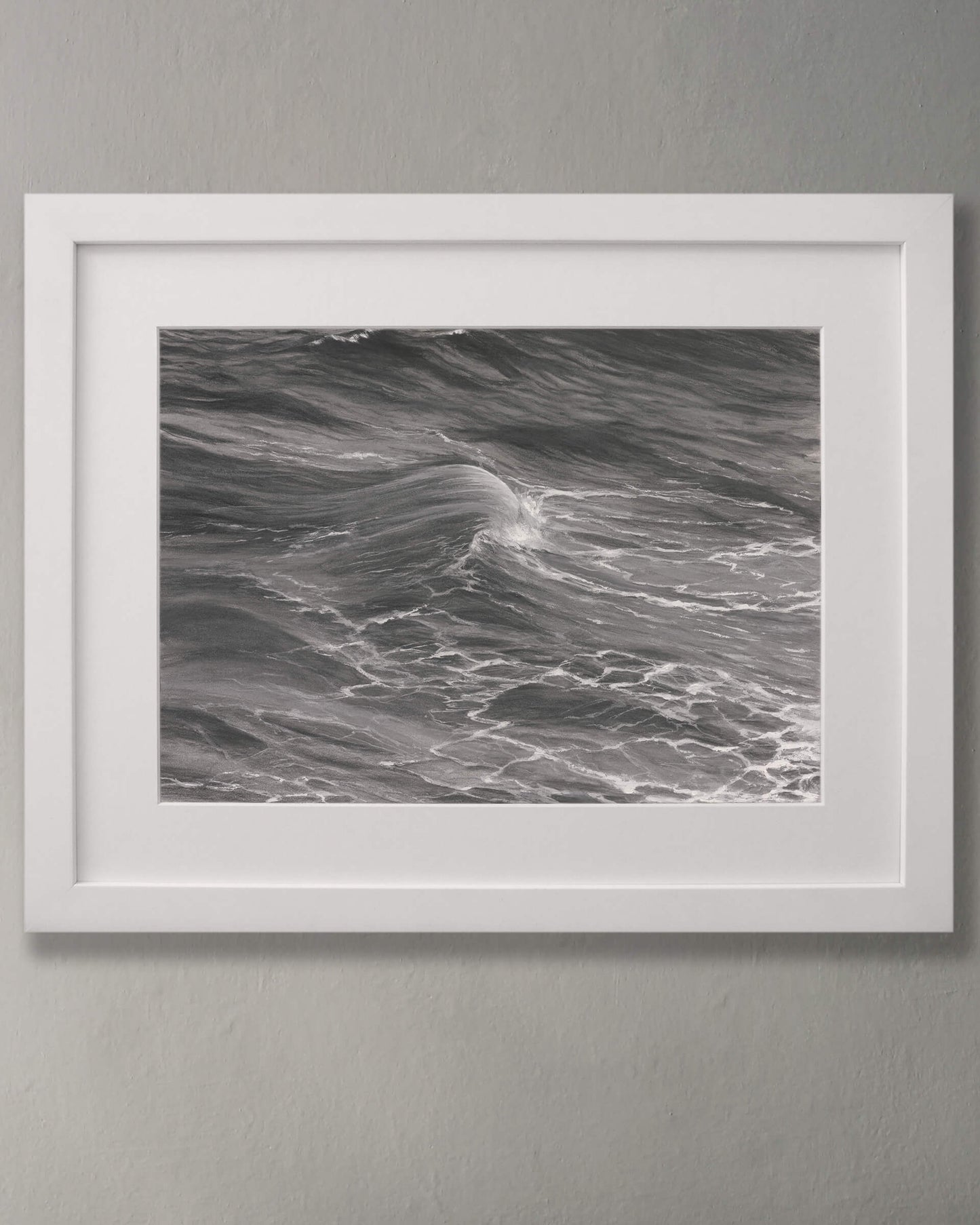 Original art, titled Rise, by Australian artist, Hayley Byron, created with graphite, charcoal, watercolour pencil, and gouache on fine art paper. This drawing is a depiction of the ocean at Tamarama, Sydney, from the viewpoint of the headland cliffs. This image features the artwork in-situ, on a wall in a frame.