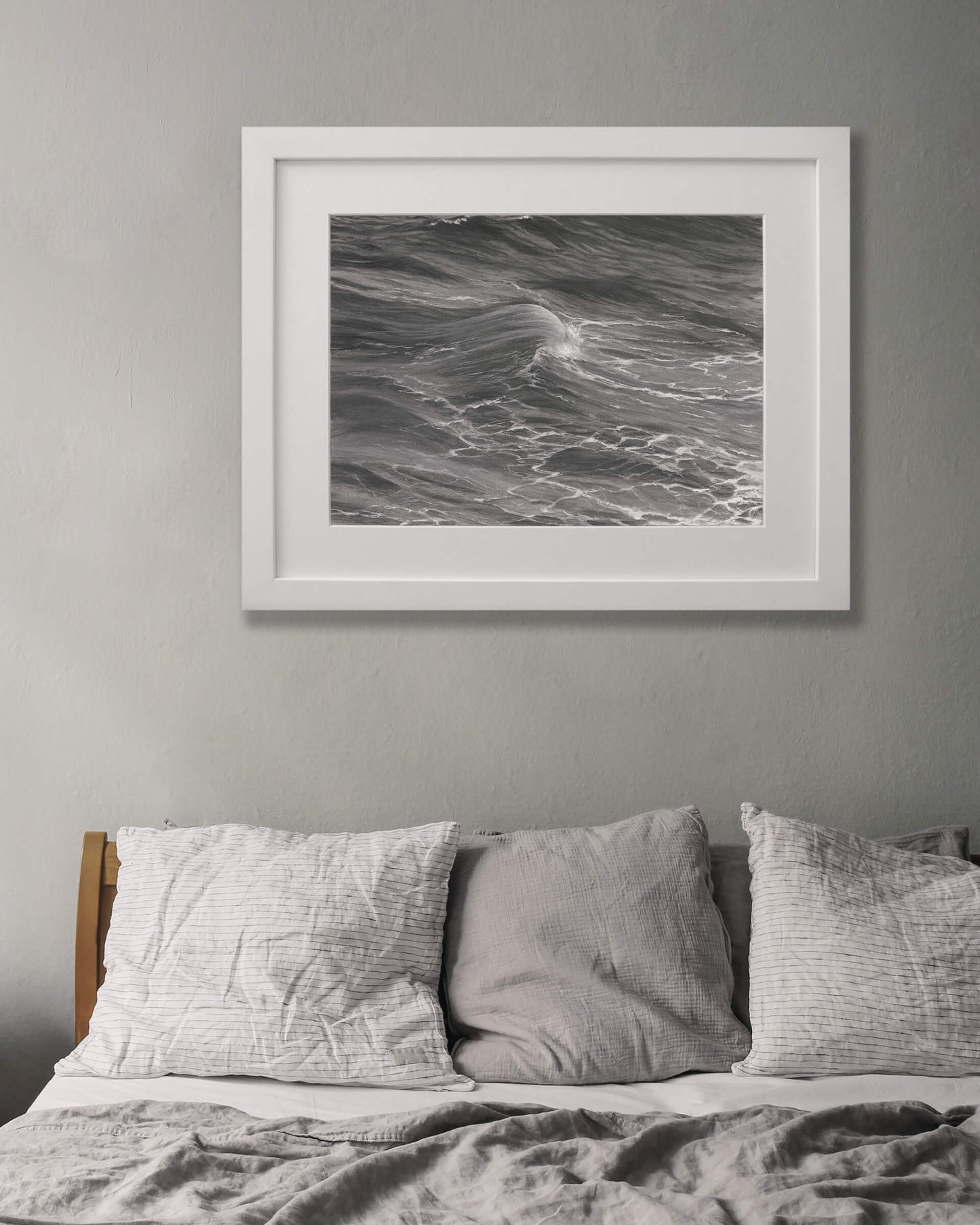 Original art, titled Rise, by Australian artist, Hayley Byron, created with graphite, charcoal, watercolour pencil, and gouache on fine art paper. This drawing is a depiction of the ocean at Tamarama, Sydney, from the viewpoint of the headland cliffs. This image features the artwork in-situ, on a wall in an interior bedroom.
