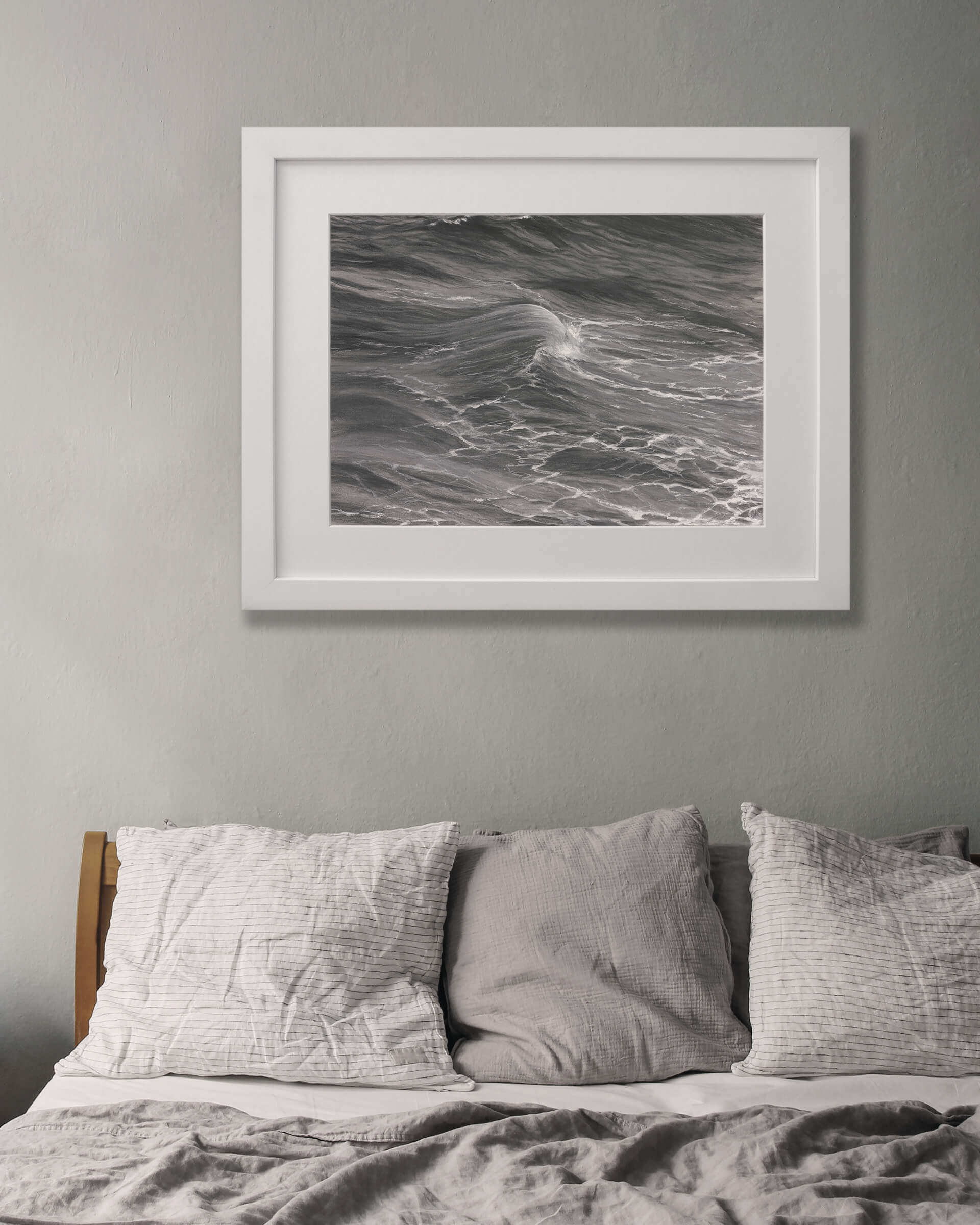 Original art, titled Rise, by Australian artist, Hayley Byron, created with graphite, charcoal, watercolour pencil, and gouache on fine art paper. This drawing is a depiction of the ocean at Tamarama, Sydney, from the viewpoint of the headland cliffs. This image features the artwork in-situ, on a wall in an interior bedroom.