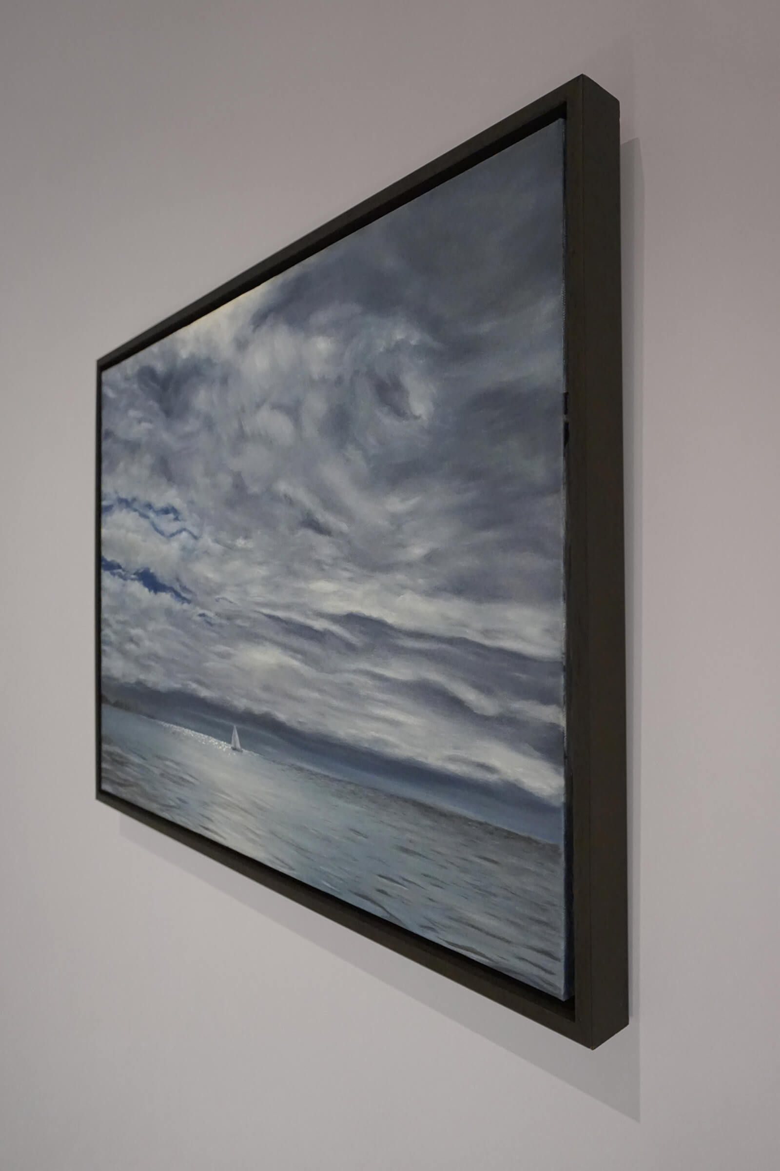 Original art, titled Yesterday, painted in oil on canvas, by Australian artist, Hayley Byron. The painting is a depiction of a ship sailing on the ocean at Burleigh Heads, in a rain storm, with high-rise buildings in the distance. This image features the artwork in-situ, on a wall in a custom-made frame.
